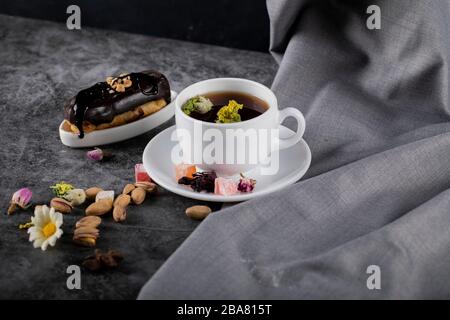 Una tazza di tè con eclair al cioccolato e pistacchi Foto Stock