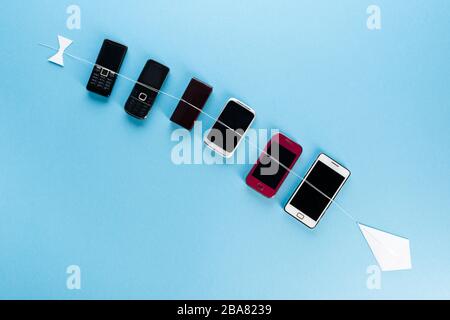 vista dall'alto dei telefoni cellulari retrò e degli smartphone moderni sul blu, concetto evolutivo Foto Stock