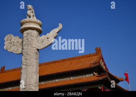 Pechino, Cina - Ottobre 2019; vista ravvicinata a basso angolo di una colonna di marmo huabiao di fronte ad uno degli iconici tetti rossi della Città Proibita di BE Foto Stock