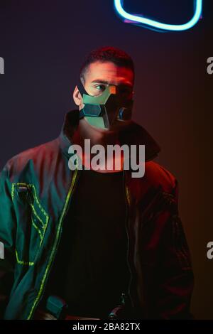 giocatore birazziale cyberpunk in maschera protettiva vicino al neon  illuminazione su nero Foto stock - Alamy