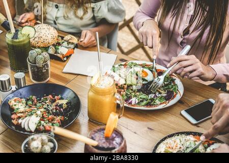 Vista dei giovani che mangiano brunch e bevono frullati ciotola con cannucce ecologiche in ristorante senza plastica - stile di vita sano, tendenza alimentare Foto Stock