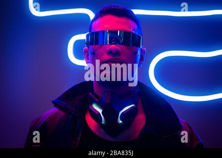 cyberpunk da corsa mista in maschera protettiva vicino all'illuminazione al  neon rossa sul nero Foto stock - Alamy