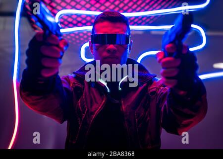 giocatore birazziale cyberpunk in maschera protettiva vicino al neon  illuminazione su nero Foto stock - Alamy