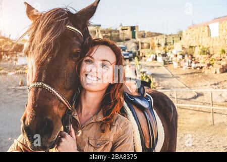 Giovane contadina donna che gioca con il suo cavallo in una giornata di sole all'interno del ranch corrale - concetto di amore tra le persone e gli animali - il fuoco principale sull'ey animale Foto Stock