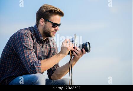 Blogger tiro vlog. Bella blogger ragazzo viaggiatore retro fotocamera. Impostazioni manuali. Concetto di fotogiornalista. Blogger di viaggio. Reporter scattare foto. Ragazzo all'aperto cielo sfondo blu. Attrezzature d'epoca. Foto Stock