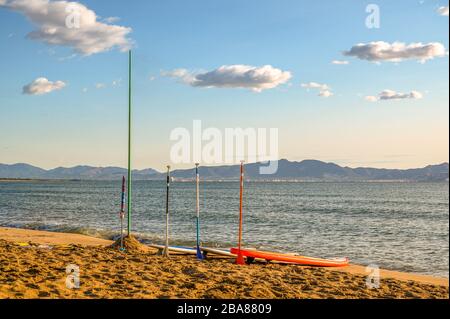 Paddle boards sulla spiaggia e una bandiera pole a Sant Marti, l'Escala Catalonia Costa Brava Spagna Foto Stock