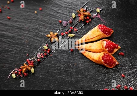 Pate di coniglio in corni croccanti decorato con spezie su un piatto di pietra nera Foto Stock