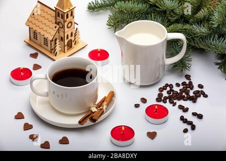 Tazza di espresso con latte, abeti, candele rosse e cioccolato su sfondo bianco. Vista dall'alto. Messa a fuoco selettiva. Decorazioni di San Valentino Foto Stock