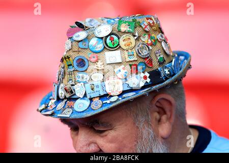 Un fan degli stand indossa un cappello coperto da vari badge davanti alla finale della Carabao Cup presso lo stadio di Wembley, Londra. Foto Stock