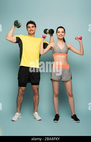 coppia atletica sorridente con manubri su blu Foto Stock