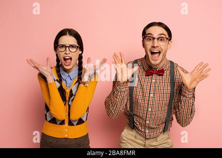 coppia di nerds scioccati negli occhiali urlando su rosa Foto Stock