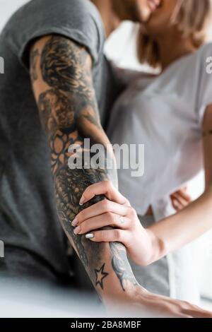 Fuoco selettivo della donna che tocca la mano OH tatoed il ragazzo a casa Foto Stock