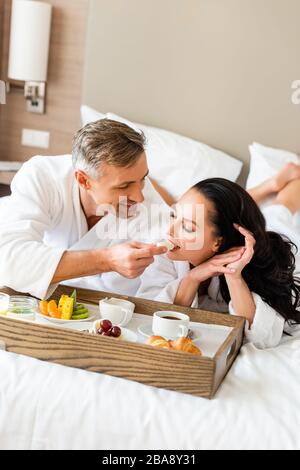 un ragazzo sorridente che si nutre di una ragazza attraente con formaggio in hotel Foto Stock