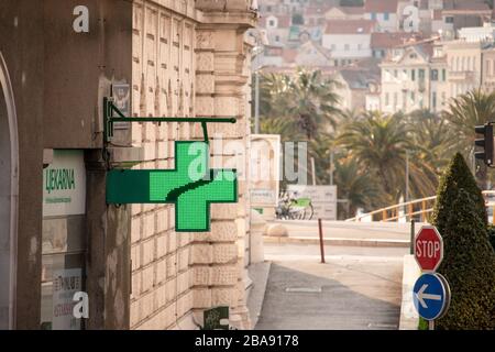 Croce verde che indica un banner del segno della farmacia. Lavorare 24/7 durante l'epidemia del virus corona Foto Stock