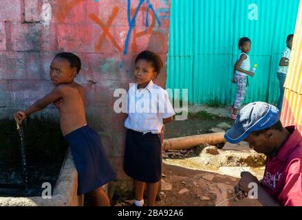 I bambini che vivono nella cittadina di Imizamo Yethu si trovano vicino al rubinetto d'acqua esterno comunale, Hout Bay, Città del Capo, Sud Africa Foto Stock