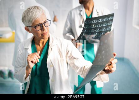 Medici che discutono la diagnosi del paziente guardando i raggi X in un ospedale Foto Stock