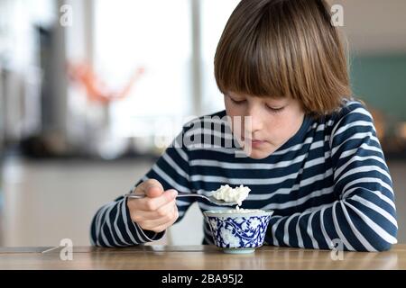 Bambini che mangiano il budino di riso al tavolo della cucina Foto Stock