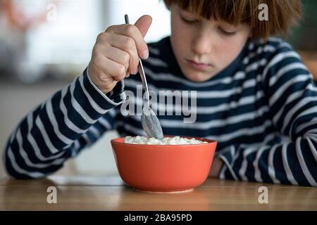 Bambini che mangiano il budino di riso al tavolo della cucina Foto Stock