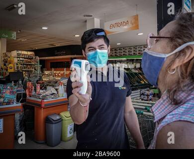 Buenos Aires, Argentina. 24 Marzo 2020. Una donna ha la sua temperatura presa prima di entrare in un supermercato. Attualmente, le persone in Argentina non sono più autorizzate a lasciare le loro case e appartamenti. Alcuni gruppi professionali sono esenti dal coprifuoco e possono continuare a lavorare: Medici, infermieri e poliziotti, dipendenti dell'industria alimentare, farmaceutica e petrolifera, dipendenti di supermercati e farmacie e dipendenti di aziende logistiche. Credit: Florencia Martin/dpa/Alamy Live News Foto Stock