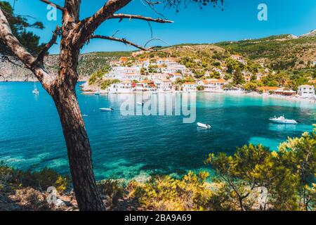 Villaggio di Assos, isola di Cefalonia Grecia. Calette turchesi con acque trasparenti del Mar Mediterraneo. Circondato da pini verdi. Motivo blu profondo Foto Stock