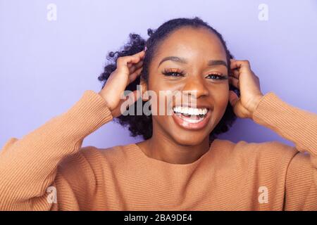 giovane allegra donna nera con le mani accanto alla testa Foto Stock