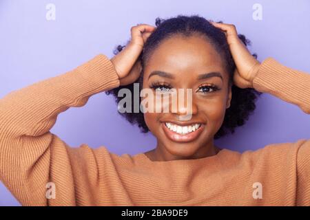 giovane allegra donna nera con le mani accanto alla testa Foto Stock