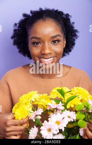 Ritratto di una bella giovane donna nera con un mazzo di fiori Foto Stock