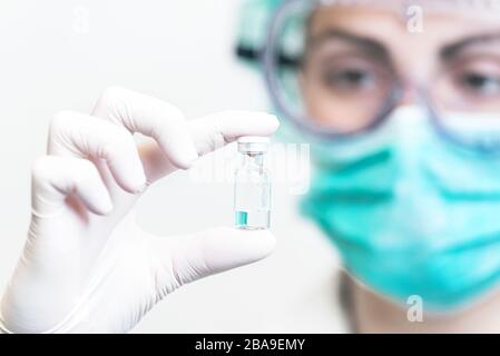 Medico o infermiere in guanti di protezione contenenti il flaconcino del vaccino per la pandemia da focolaio di Coronavirus. Medicina e concetto di droga . Foto Stock