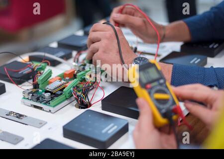 Due giovani ingegneri bello lavorare su componenti elettronici.Tech Test elettronici nel centro di servizio. Tecnologicamente avanzati strumenti scientifici Foto Stock