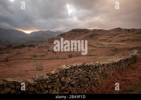 Tramonto sul Passo di Wrynose con muro di pietra a secco in primo piano, da Loughrigg, Lake District, Regno Unito Foto Stock