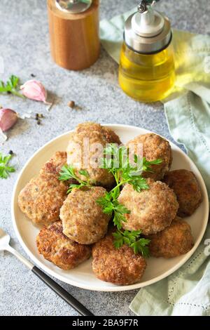 Succulenti e deliziosi tagli di carne fatti in casa nel piatto, polpette di carne tritata su un tavolo di pietra grigia. Foto Stock