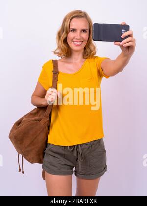 Ritratto di felice bella donna turistica bionda con zaino prendere selfie Foto Stock