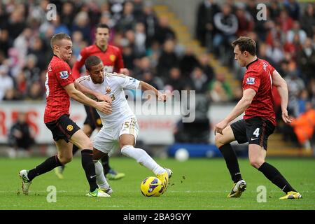 Wayne Routledge (al centro) di Swansea City battaglie per il pallone con Phil Jones (a destra) e Tom Cleverley (a sinistra) del Manchester United Foto Stock