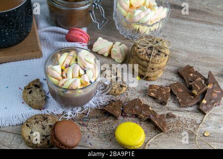 Cacao con marshmallows e forno al cioccolato, muffin e fette di cioccolato si trovano su un tavolo di legno Foto Stock