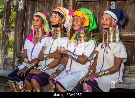 Quattro Padaung donne in abito tradizionale e con anelli di metallo intorno al collo sono seduti accanto l'uno all'altro nel villaggio.12 febbraio, 2019, Myanmar Foto Stock