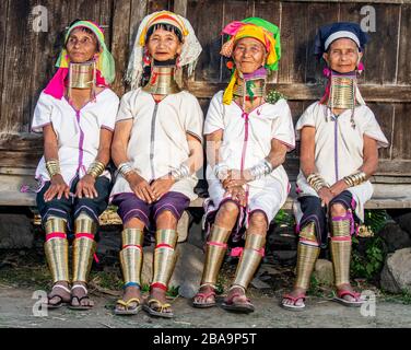 Quattro Padaung donne in abito tradizionale e con anelli di metallo intorno al collo sono seduti accanto l'uno all'altro nel villaggio.12 febbraio, 2019, Myanmar Foto Stock