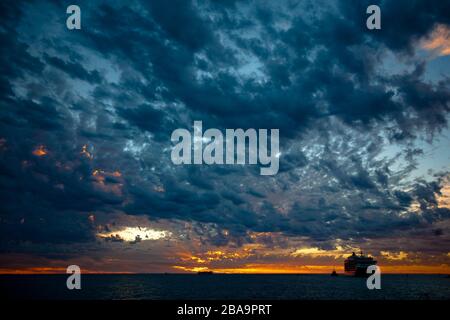 Una crociera ancorò i terreni offshore in un epico tramonto rosso sangue. Australia occidentale Foto Stock