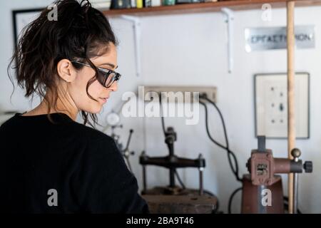Ritratto di profilo di gioielliere femminile che lavora in studio casa ben illuminato Foto Stock
