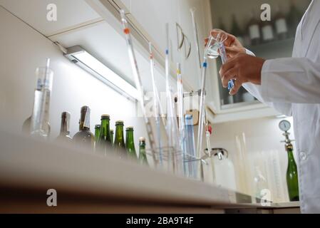 Primo piano delle mani del tecnico posizionando un campione sulla provetta di dosaggio. Foto Stock