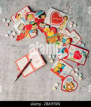 Vista dall'alto delle carte e delle caramelle vintage di San Valentino su sfondo grigio. Foto Stock