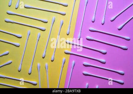 Bastoncini di cotone su sfondo rosa e giallo. Bastoncini di cotone e concetto di pulizia delle orecchie. Foto Stock