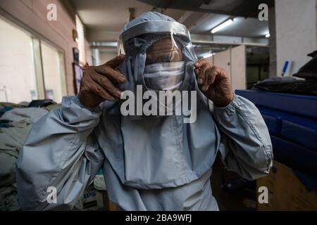 Un uomo prova su una nuova tuta protettiva.Patan Hospital produce vestiti di PPE (produzione di dispositivi di protezione individuale) durante il blocco imposto dal governo tra le preoccupazioni circa la diffusione della malattia del virus corona (COVID-19) focolaio. L'ospedale sta attualmente producendo circa 8 tute PPE al giorno. Foto Stock