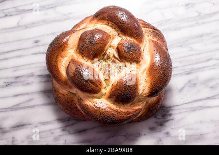 Pane intrecciato di Challah rotondo con semi di papavero Foto Stock