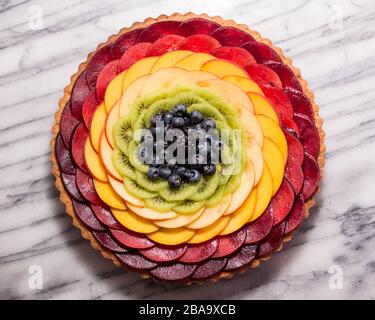 Arcobaleno frutta Tart su un tavolo di pasticceria in marmo Foto Stock