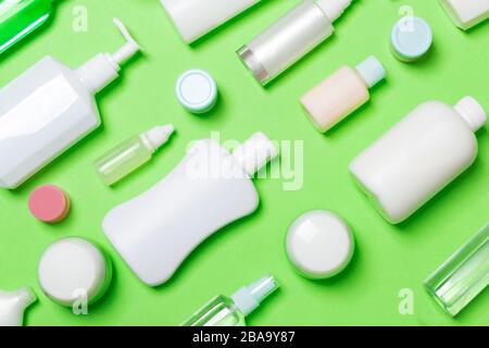 Vista dall'alto di diversi flaconi cosmetici e contenitore per prodotti cosmetici su sfondo verde. Piano di composizione dei laici con copia spazio. Foto Stock