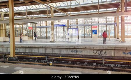 Amsterdam, Olanda 25 marzo 2020 : una manciata di persone aspettano sulla piattaforma quasi vuota mentre si pratica il sociale a distanza Amstel Station durante l'ora di punta, seguendo le regole più severe da parte del governo olandese per combattere la crisi corvida-19. Foto Stock