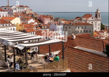 Lisbona, Portogallo 8 marzo 2020: Persone che bevono in un bar sulla terrazza con lo skyline di Lisbona sullo sfondo Foto Stock