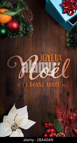 "Joyeux Noel et Bonne Année" t.i. Buon Natale e felice anno nuovo in lingua francese su uno sfondo di legno con decorazione verticale vista per l'intelligenza Foto Stock