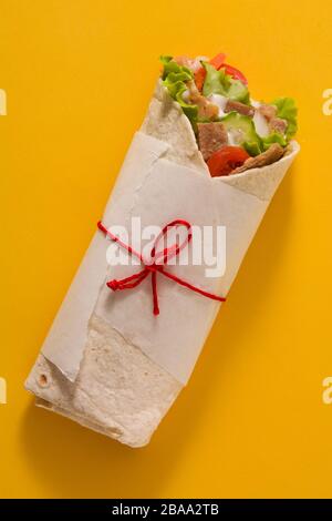 Doner kebab o shawarma sandwich isolato su sfondo giallo. Vista dall'alto. Foto Stock