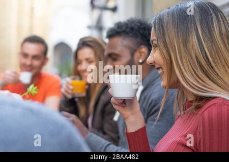 Millenni multietnici che trascorrono del tempo in un bar. I giovani si divertono bevendo cappuccino e succo di frutta Foto Stock